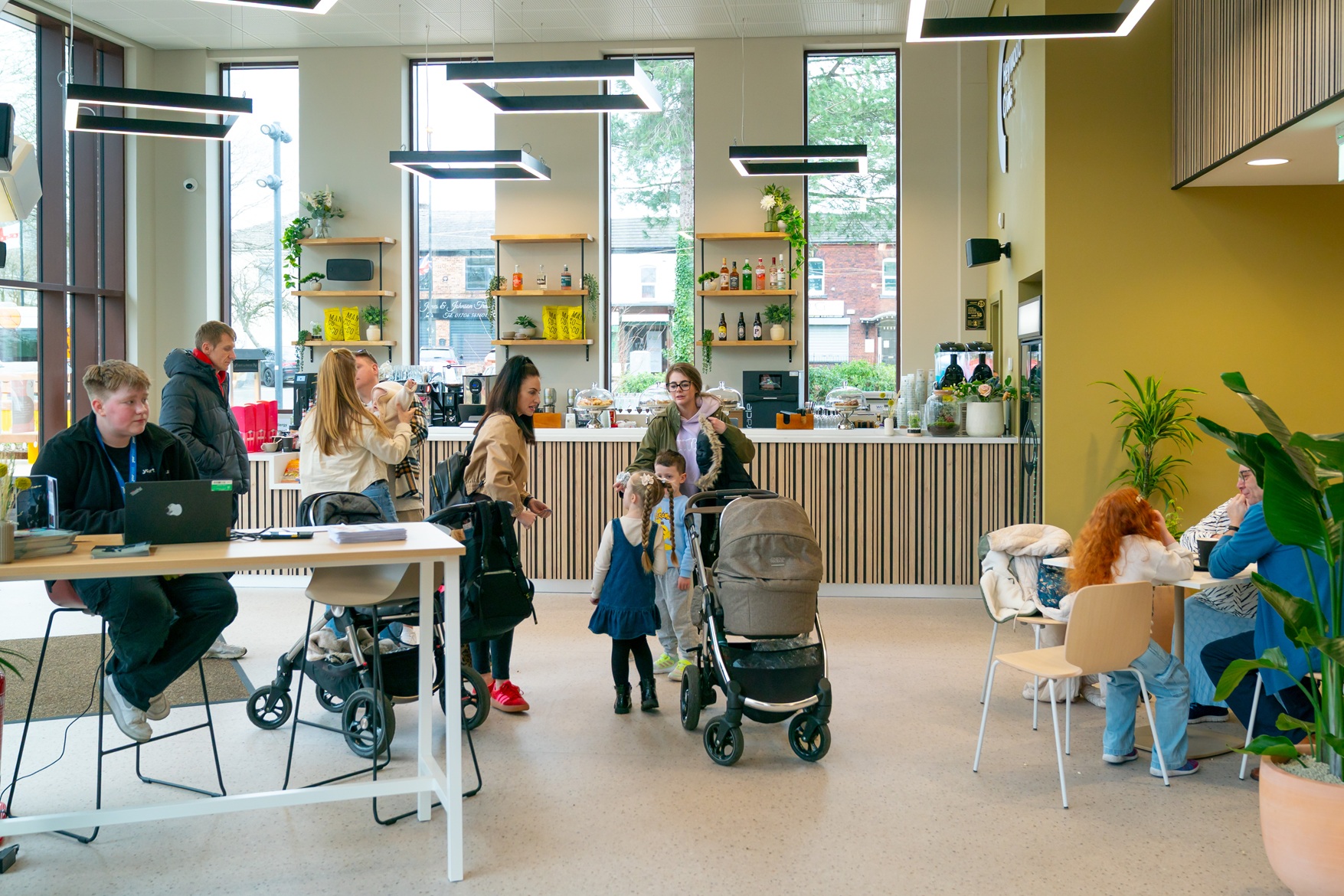 Interior view of the new Bar + Kitchen at Heywood Civic, featuring a modern bar counter, contemporary lighting, and local families and community members gathered at tables and socialising in the space.