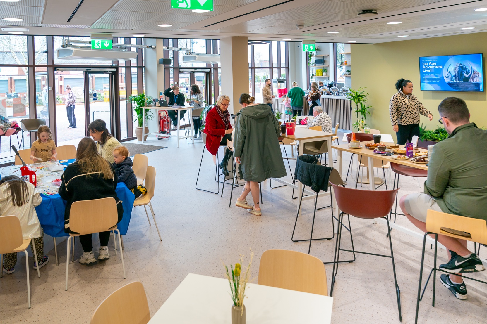 Interior view of the new Bar + Kitchen at Heywood Civic, featuring a modern bar counter, contemporary lighting, and local families and community members gathered at tables and socialising in the space.
