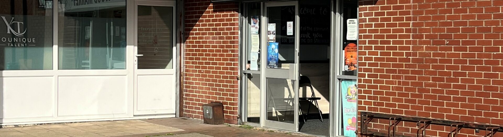 An image of the entrance for Daisy's Cafe in Heywood. The entrance is to the Heywood Market which is in a white sign and is on a brown brick building.