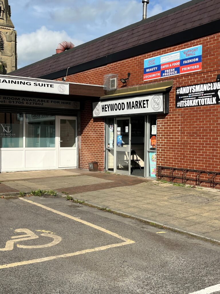 An image of the entrance for Daisy's Cafe in Heywood. The entrance is to the Heywood Market which is in a white sign and is on a brown brick building.